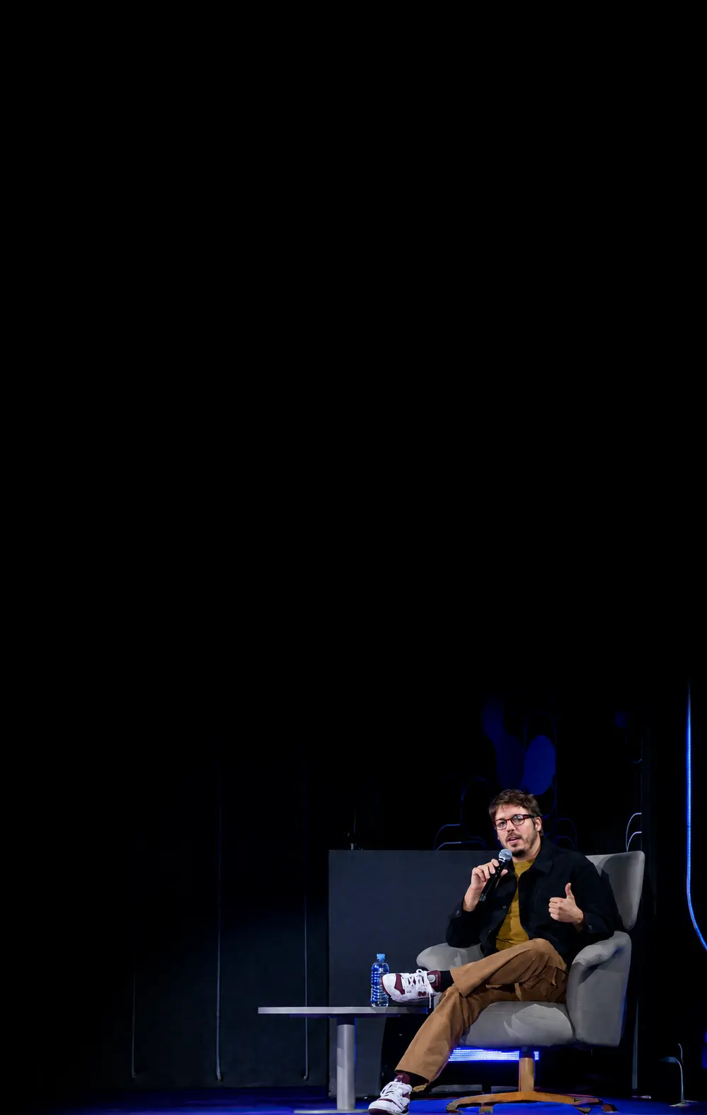 Executiva discursando com microfone em evento corporativo